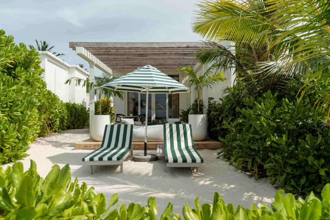 Sun Siyam Iru Veli, Dhaalu Atoll — villa exterior with a timber pergola, a striped parasol and two loungers on the sand between dense planting