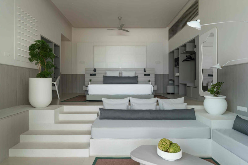 A bedroom at Sun Siyam Iru Veli with grey wall panelling, the bed on a raised platform and a mirror beside the wardrobe.