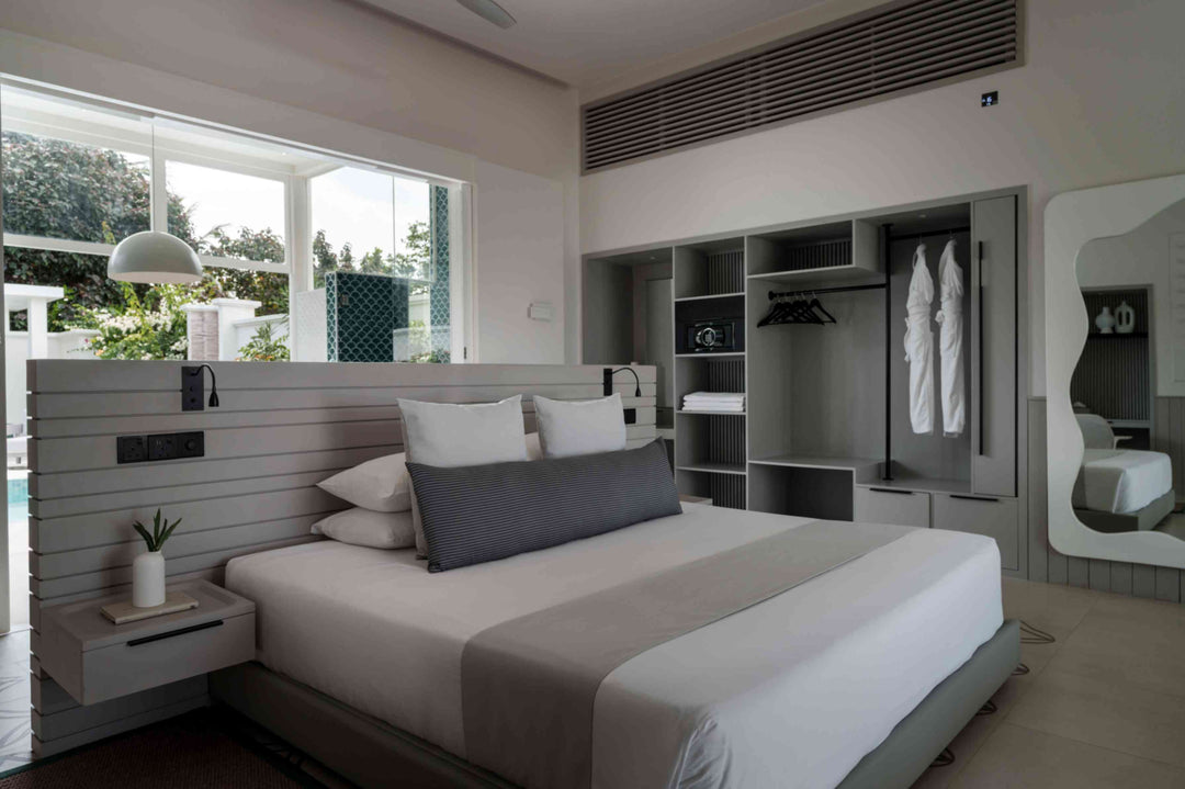 Sun Siyam Iru Veli, Dhaalu Atoll — bedroom with grey panelling, an open wardrobe holding robes, shelving and a mirror