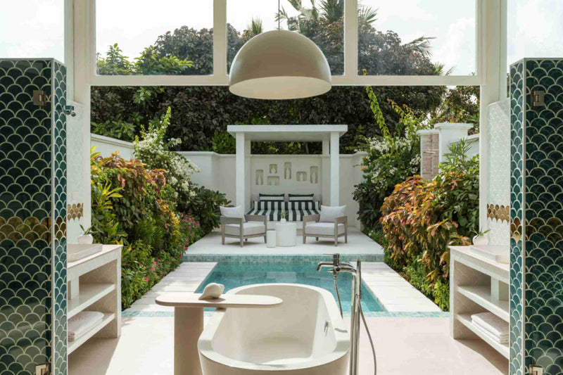 An open-air bathroom pavilion at Sun Siyam Iru Veli with teal fish-scale columns and a freestanding tub beside the pool.