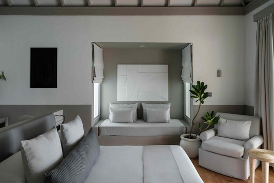 Sun Siyam Iru Veli, Dhaalu Atoll — bedroom with grey panelling, a white upholstered headboard and a bench at the foot of the bed
