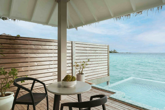 Sun Siyam Iru Veli, Dhaalu Atoll — overwater deck with a table and chairs behind a timber screen, pool at the edge
