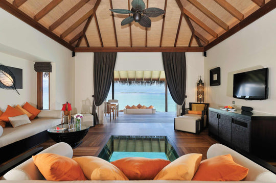 A sunset ocean suite sitting area at Ayada Maldives with orange cushions and the pool beyond
