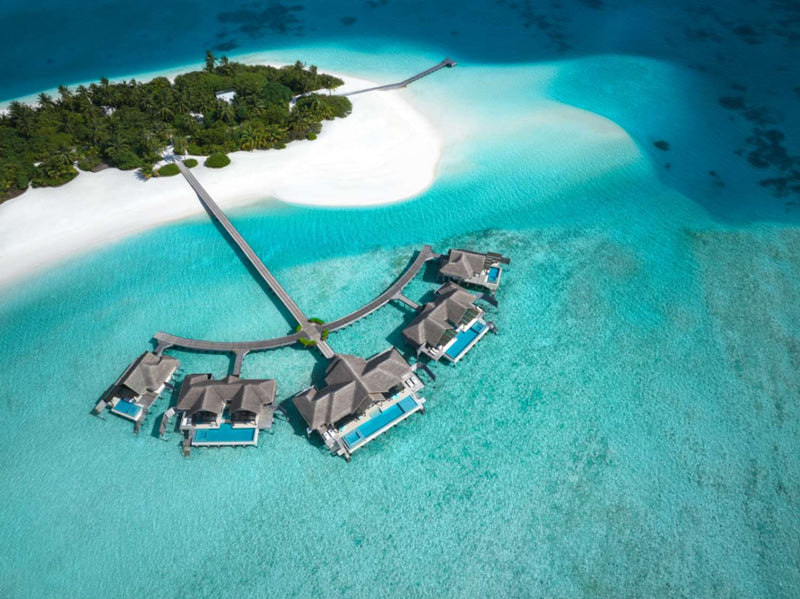 The Crescent at Niyama Private Islands seen from the air, a curving run of overwater pavilions