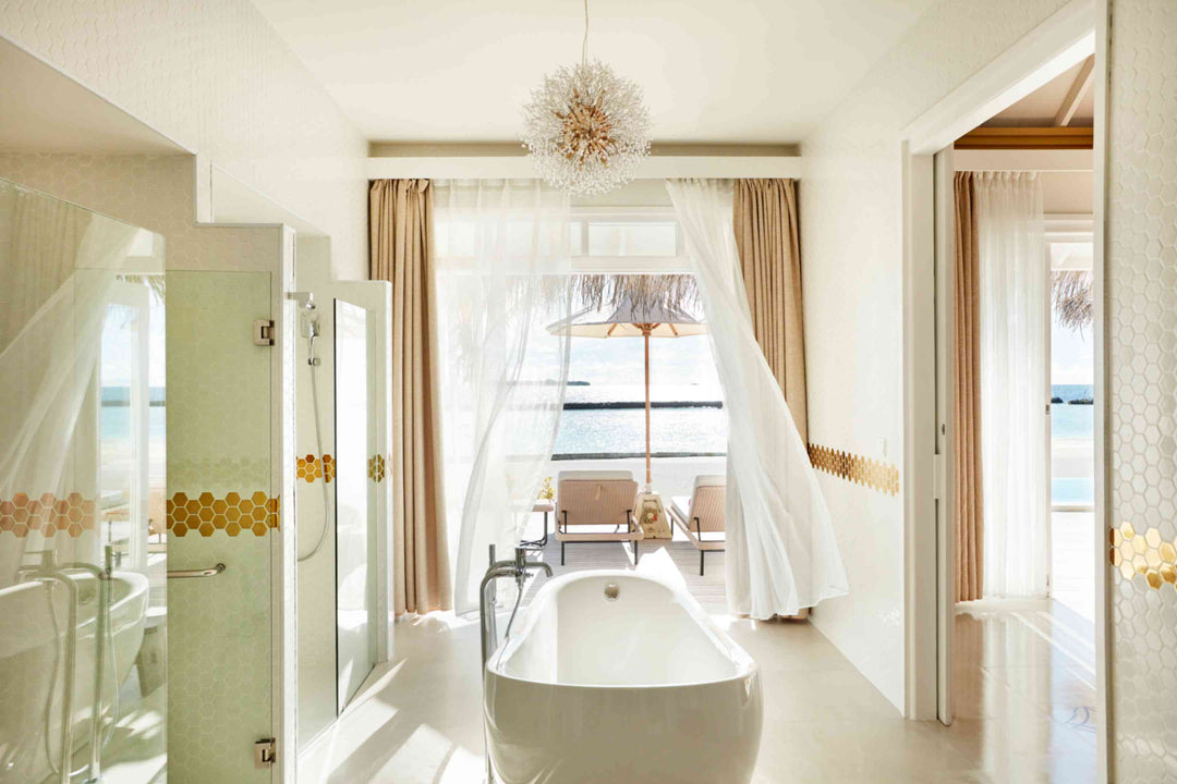 Sun Siyam Iru Veli, Dhaalu Atoll — bathroom with a freestanding tub and chandelier, doors open to a deck and the sea