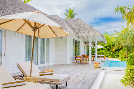 Sun Siyam Iru Veli, Dhaalu Atoll — beach villa exterior with a thatched roof, loungers on the deck and a plunge pool