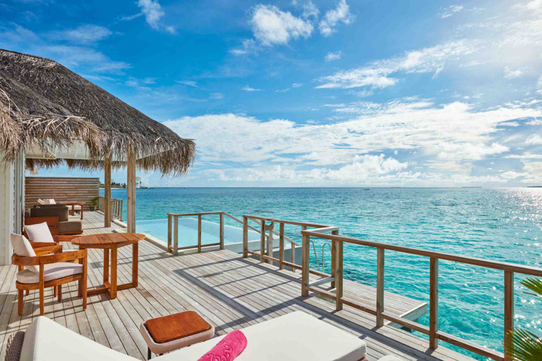 Sun Siyam Iru Veli, Dhaalu Atoll — overwater deck under a thatched shade, daybed and chairs looking over the lagoon