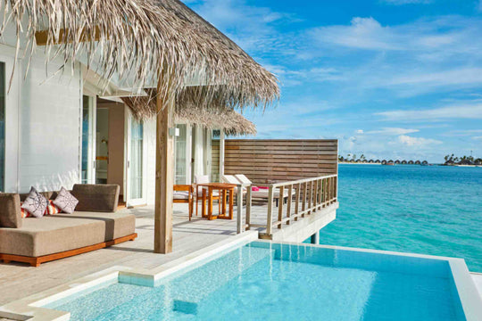 Sun Siyam Iru Veli, Dhaalu Atoll — overwater villa deck behind a timber screen, sofa and pool at the lagoon edge