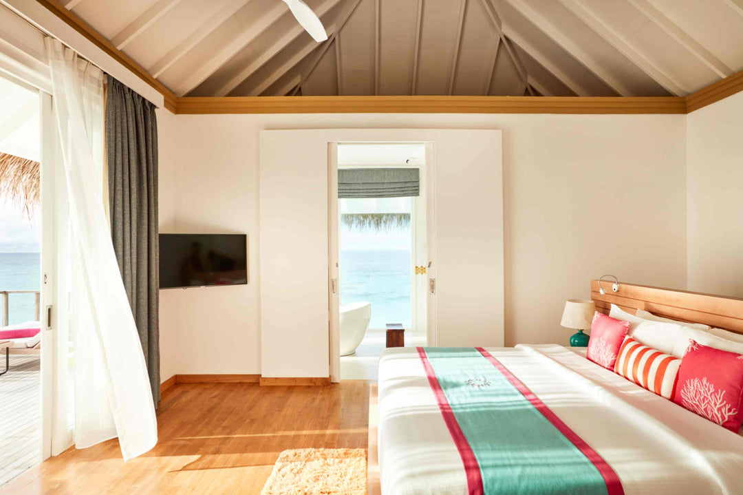 Sun Siyam Iru Veli, Dhaalu Atoll — bedroom with the bed facing open doors to the sea, and the bath visible beyond