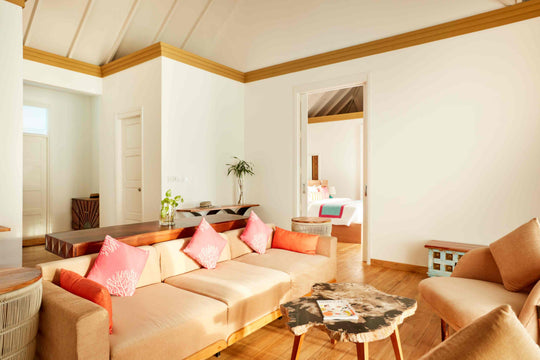 Sun Siyam Iru Veli, Dhaalu Atoll — living area with a long sofa in coral cushions and a hide rug