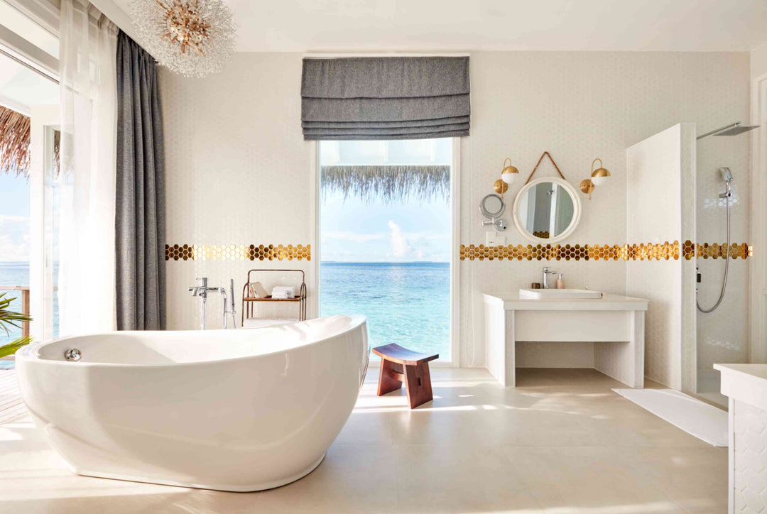 Sun Siyam Iru Veli, Dhaalu Atoll — bathroom with a large freestanding tub and a round mirror, looking out to the lagoon