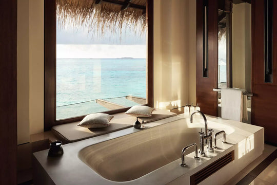 Bathroom of a One&amp;Only Reethi Rah Water Villa with Pool, the bath set below a window looking straight onto the lagoon