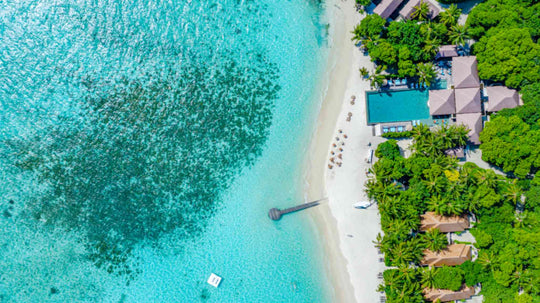 The pool and beach area at Ayada Maldives from above, loungers set along the sand