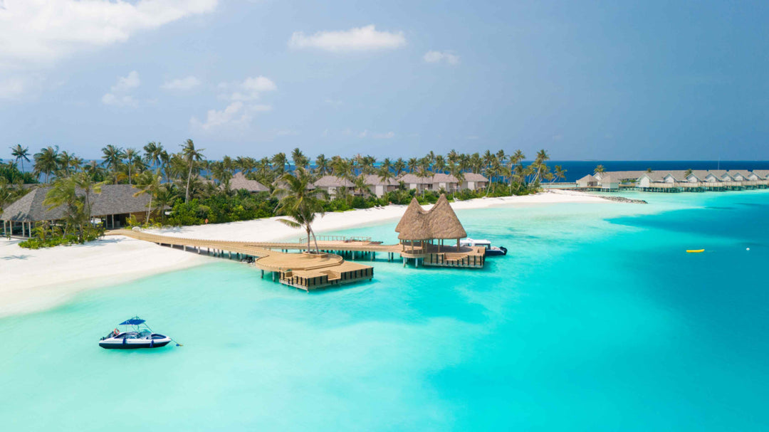 The overwater restaurant and jetty at ananea Madivaru Maldives from the air, a boat moored on the sand