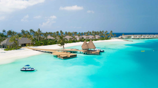 The overwater restaurant and jetty at ananea Madivaru Maldives from the air, a boat moored on the sand
