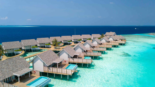 The overwater villas at ananea Madivaru Maldives from the air, each with a pool, strung out along the reef edge