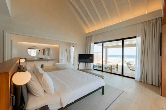 A bedroom at ananea Madivaru Maldives, the bed facing sliding doors that open on to the deck and the sea