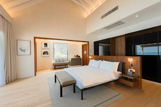 A villa bedroom at ananea Madivaru Maldives, bed with a long bench at its foot and framed prints on the wall
