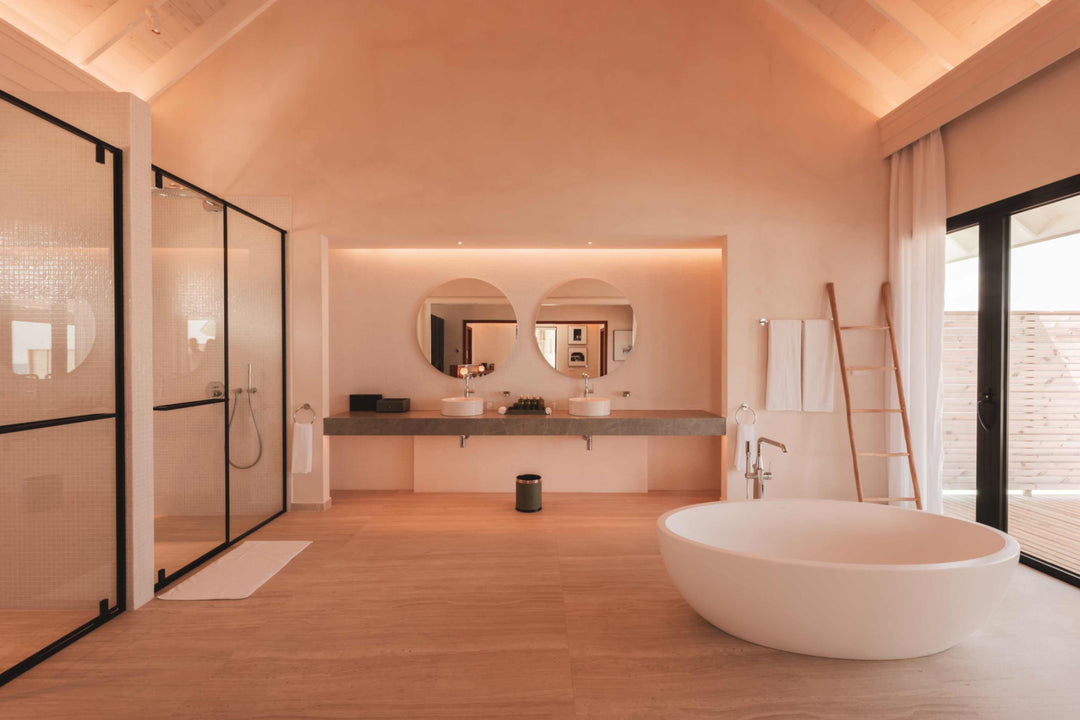 A villa bathroom at ananea Madivaru Maldives, freestanding bath beside twin basins and a walk-in shower