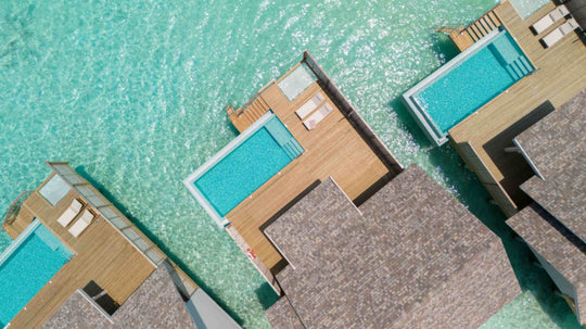 Two overwater villas at ananea Madivaru Maldives from the air, their pools and decks over clear shallow water