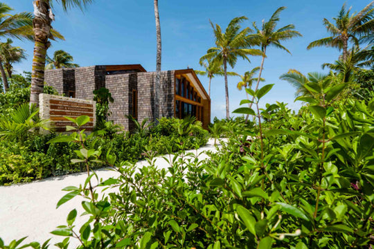 The timber and stone entrance to a building at ananea Madivaru Maldives, set among dense planting