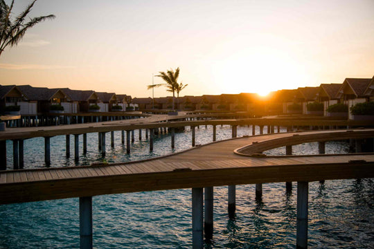 Sunset behind the overwater villas at ananea Madivaru Maldives, seen along the timber walkway