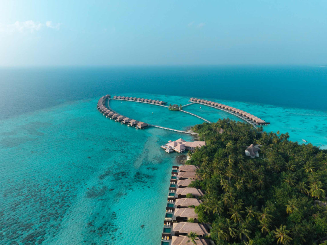 Ayada Maldives from a distance, the overwater villas a thin line on the pale lagoon
