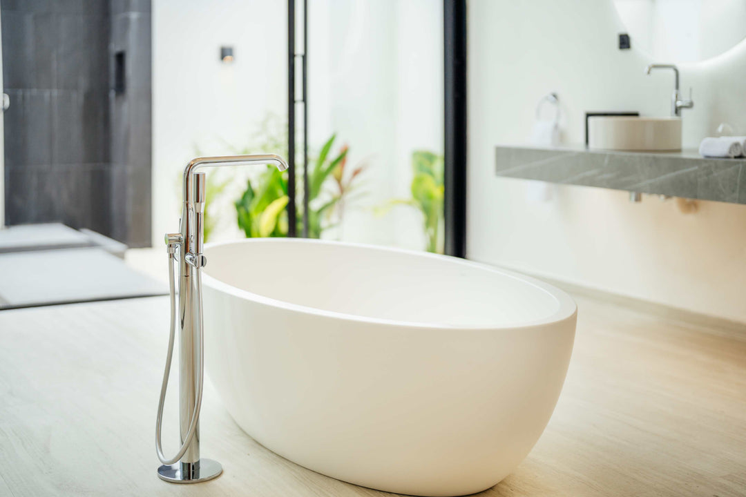 A freestanding bath in a villa bathroom at ananea Madivaru Maldives, greenery beyond the glass