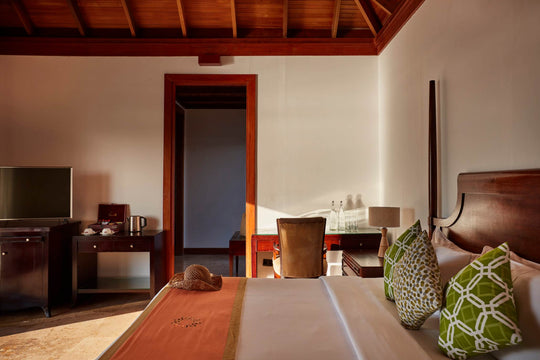 Sun Siyam Olhuveli, South Malé Atoll — Prestige Jacuzzi Water Villa bedroom under a timber ceiling