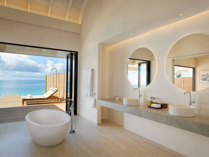The bathroom of a Water Pool Villa at ananea Madivaru Maldives, twin basins with the lagoon through the open doors