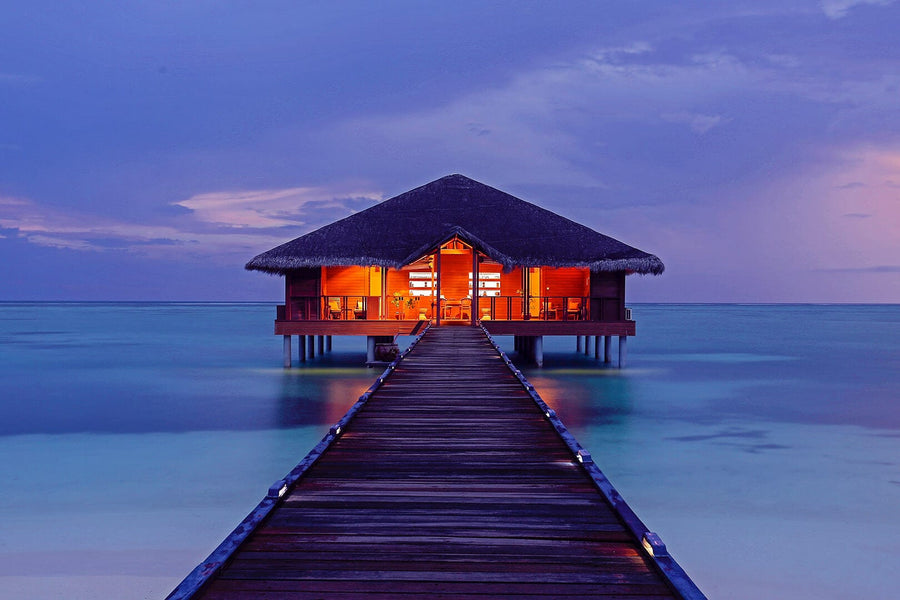The overwater spa lit at dusk at the end of its jetty, Medhufushi Island Resort