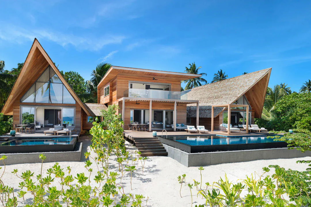 The St. Regis Maldives Vommuli, Dhaalu Atoll — Beach villa of A-frame timber pavilions with a dark-tiled pool behind low greenery