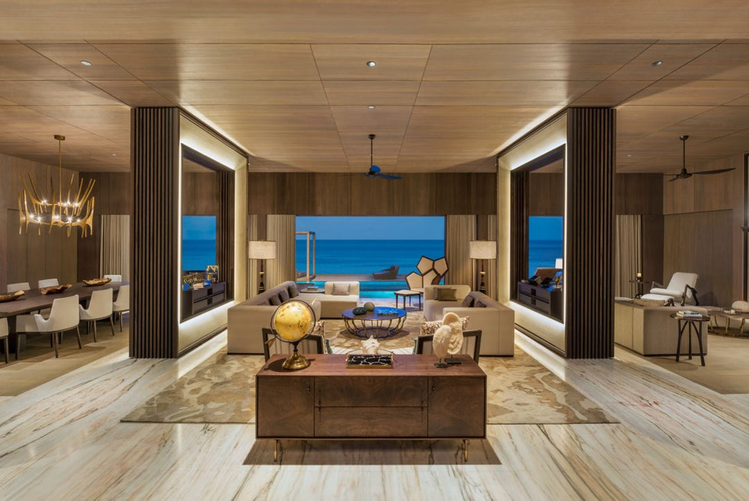 The St. Regis Maldives Vommuli, Dhaalu Atoll — Living room with pale timber floors and sea views on two sides, dining area beyond