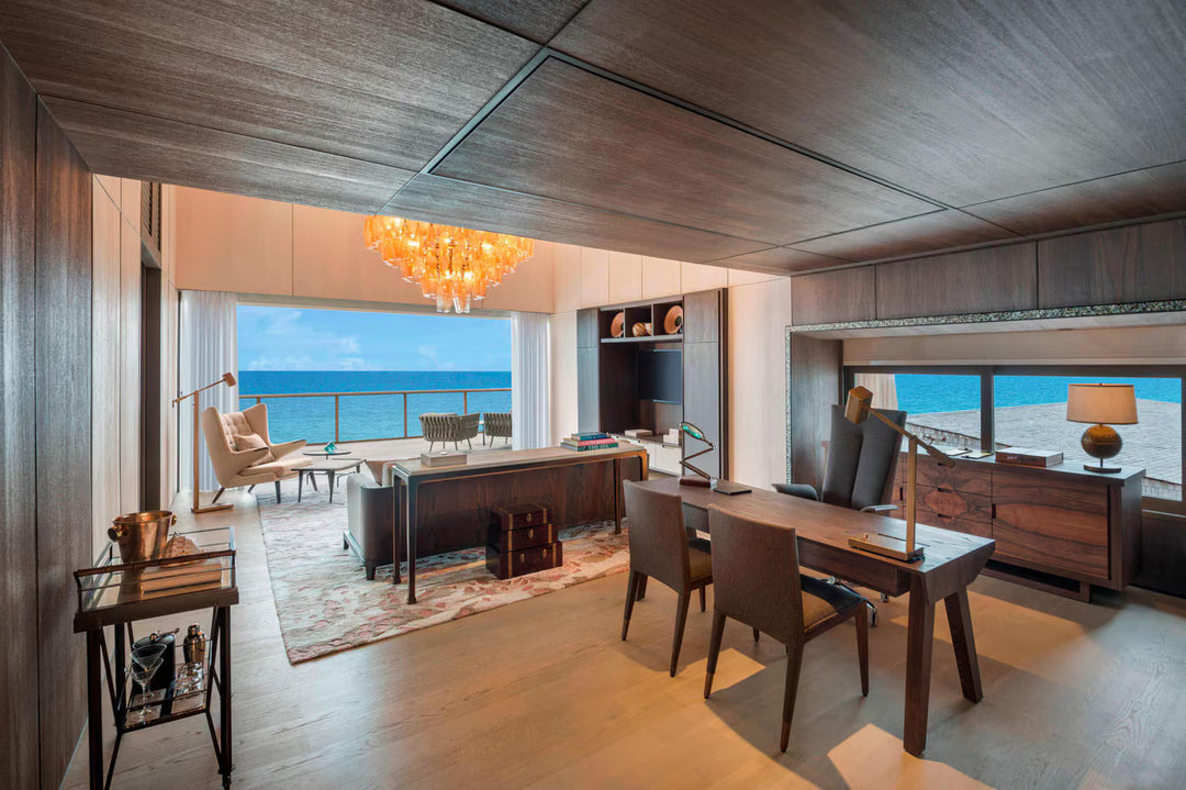 The St. Regis Maldives Vommuli, Dhaalu Atoll — Suite living area with a writing desk, a chandelier and a sea view through full-height glass