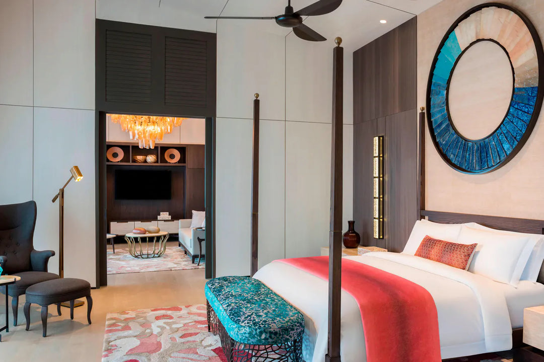 The St. Regis Maldives Vommuli, Dhaalu Atoll — Bedroom with a four-poster bed, a round mirror and a television alcove