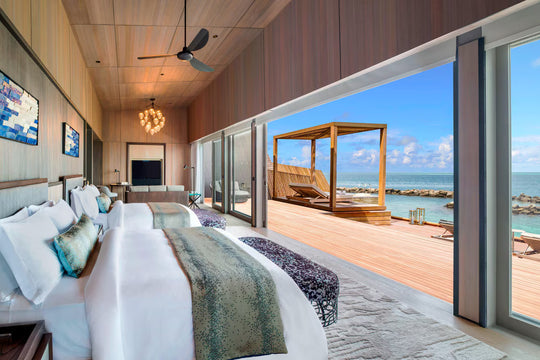 The St. Regis Maldives Vommuli, Dhaalu Atoll — Bedroom looking out to a deck with a shaded daybed and the sea beyond