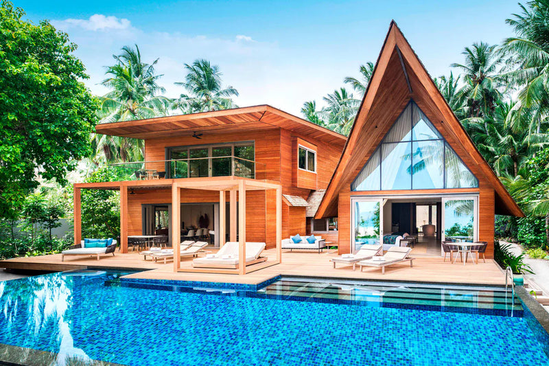 A two-storey beach residence at The St. Regis Maldives Vommuli with a large pool, loungers and a glass gable.