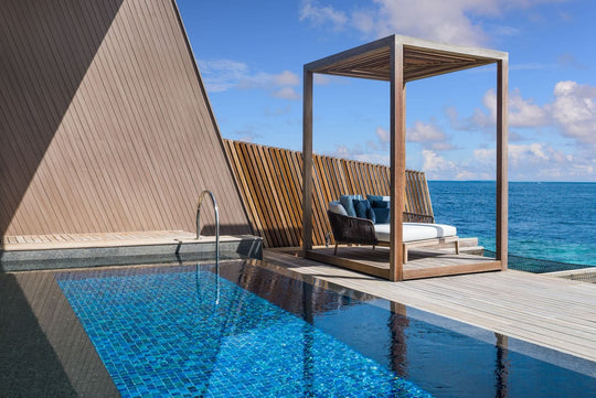 The St. Regis Maldives Vommuli, Dhaalu Atoll — Shaded cabana and daybed beside a private pool on an overwater deck