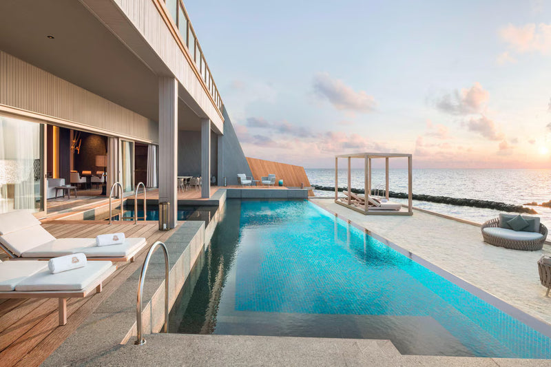 A villa deck at The St. Regis Maldives Vommuli with a long private pool, loungers and the sea beyond.
