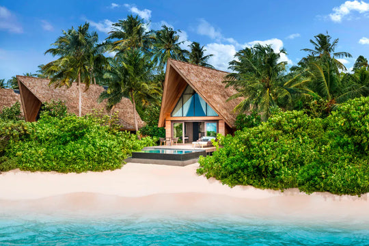 The St. Regis Maldives Vommuli, Dhaalu Atoll — Beach villa in dense greenery on white sand, seen from the water