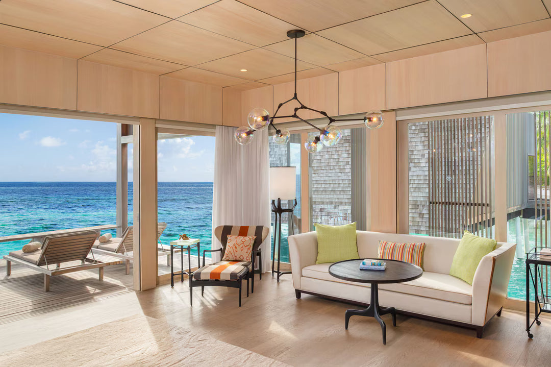 The St. Regis Maldives Vommuli, Dhaalu Atoll — Living room with sofas, a chandelier and glass onto the lagoon