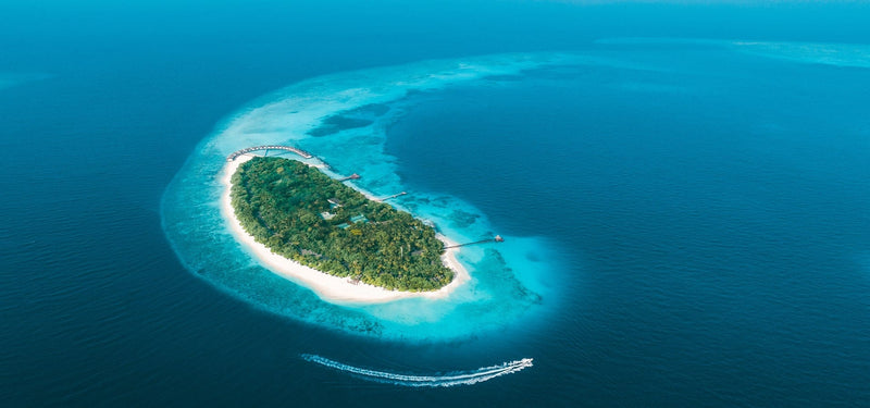 NH Collection Maldives Reethi Resort from the air, the island ringed by white sand.