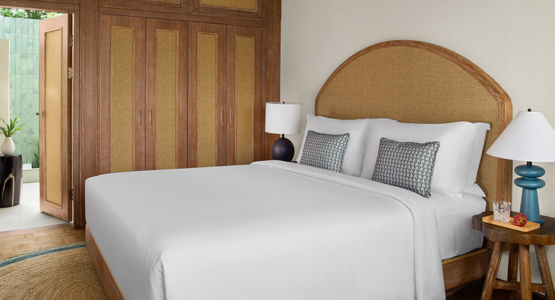 The bed in a Deluxe Sunset Villa at NH Collection Maldives Reethi Resort.