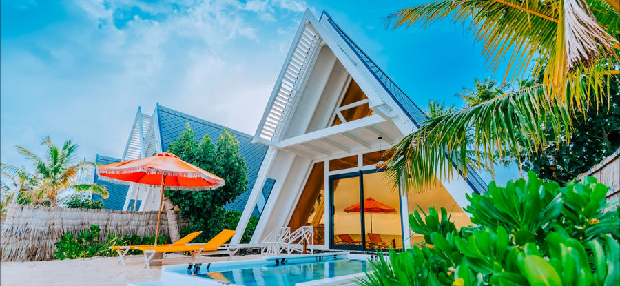 A Bodu Haruge Beach Villa at Oaga Art Resort, its white A-frame roof above a private pool and sunloungers