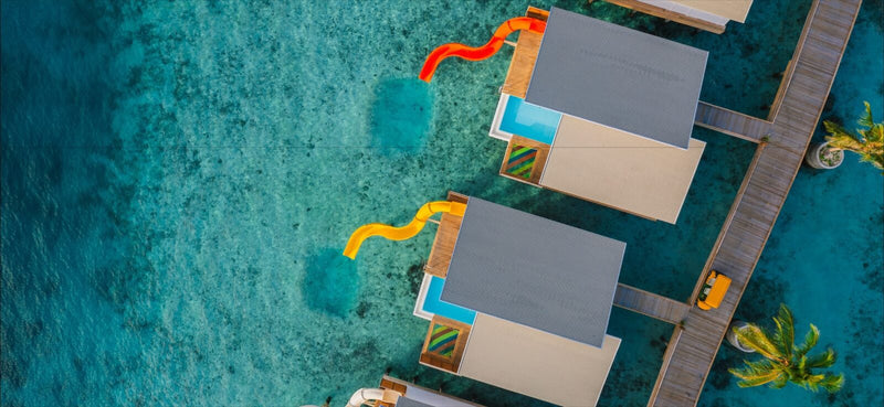 Odi Water Villas at Oaga Art Resort from above, each with a private pool and an orange slide into the lagoon