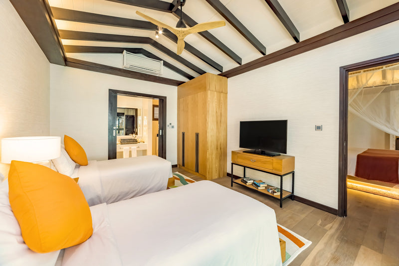 The twin-bed second bedroom of a two-bedroom Earth Pool Pavilion at OZEN LIFE Maadhoo, two single beds under a beamed ceiling