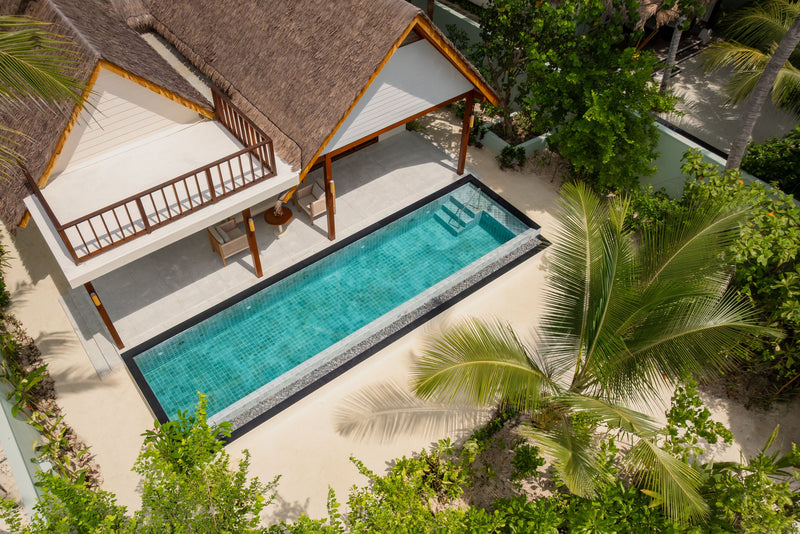 An Earth Pool Residence at OZEN LIFE Maadhoo from above, its long turquoise pool beside the thatched villa among the palms