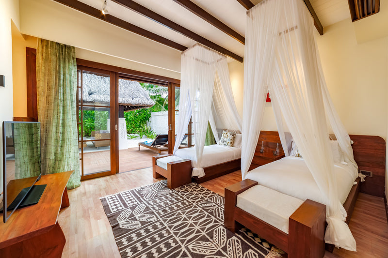 The twin bedroom of a two-bedroom Earth Pool Pavilion at OZEN RESERVE BOLIFUSHI, two canopied single beds with doors open to the garden deck