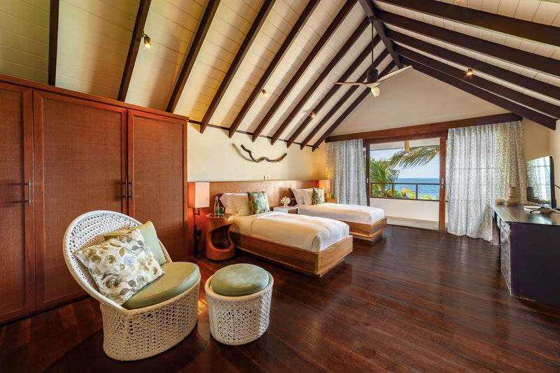 The twin bedroom of a two-bedroom Earth Pool RESERVE at OZEN RESERVE BOLIFUSHI, two single beds under a vaulted timber ceiling with a sea view from the balcony