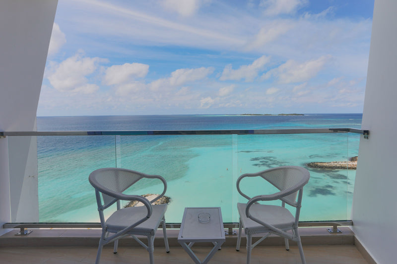 Balcony with two chairs above a turquoise lagoon at Kaani Palm Beach